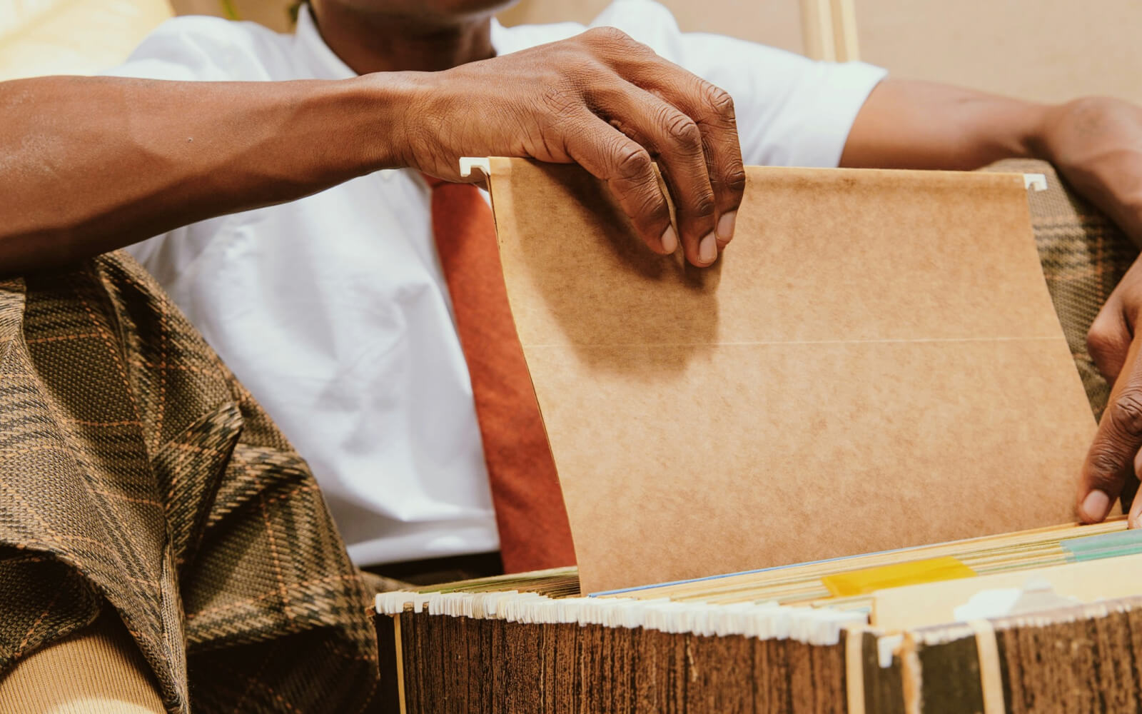 Hiring manager flipping through paper candidate files in a filing box